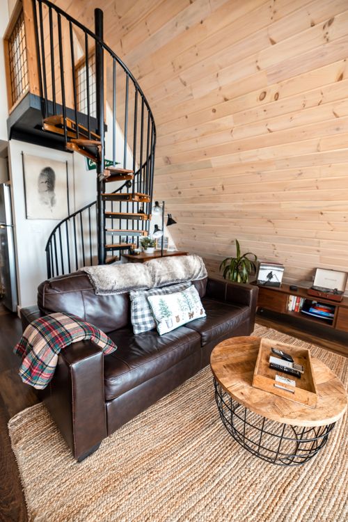 Free Minimalist living room featuring a leather sofa and spiral staircase in modern design. Stock Photo