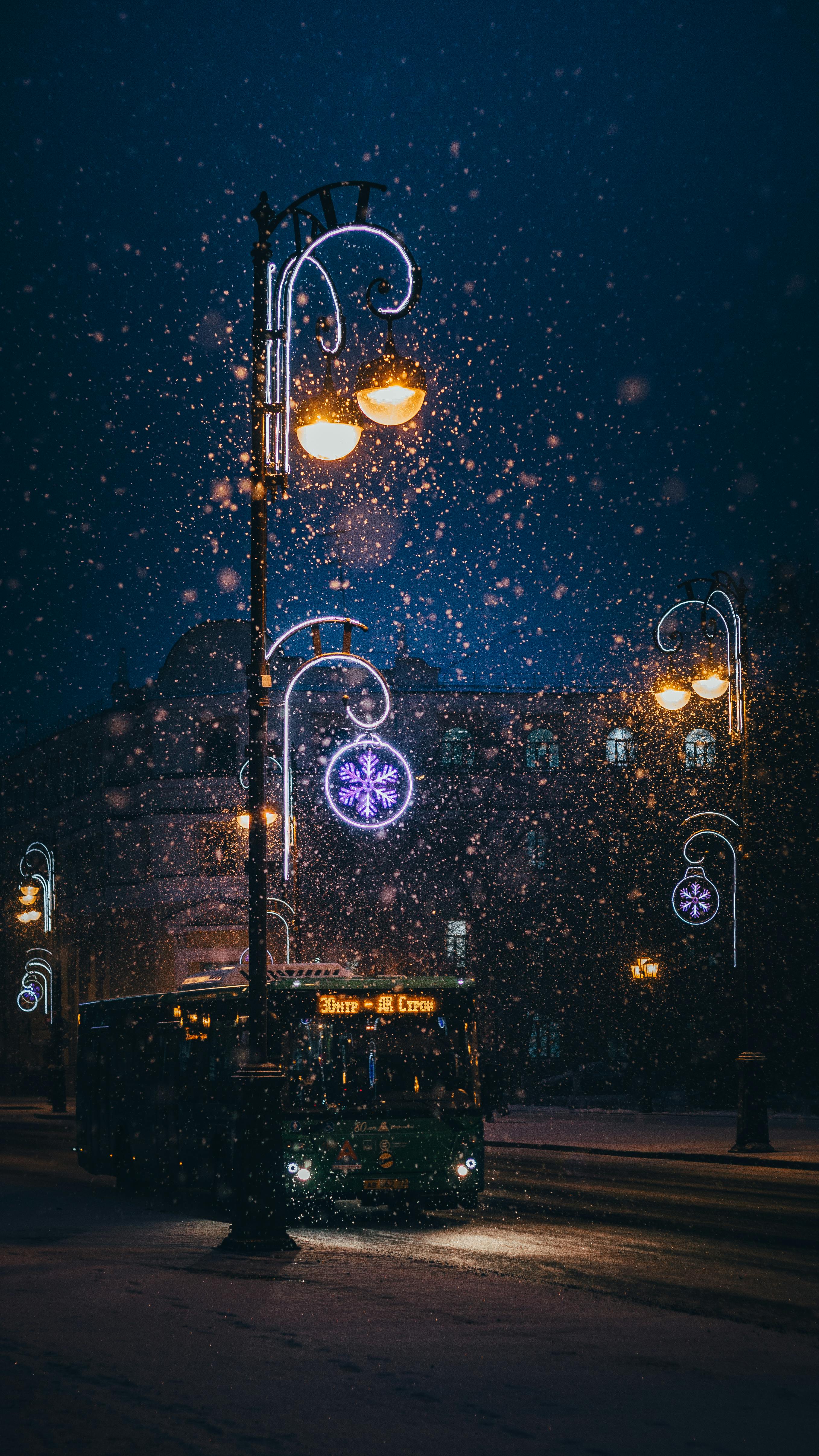 Captivating snowy evening scene featuring a bus and decorated street lamps in winter.