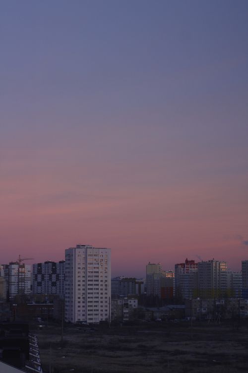 Free A serene cityscape at twilight featuring a colorful sunset sky and modern buildings. Stock Photo