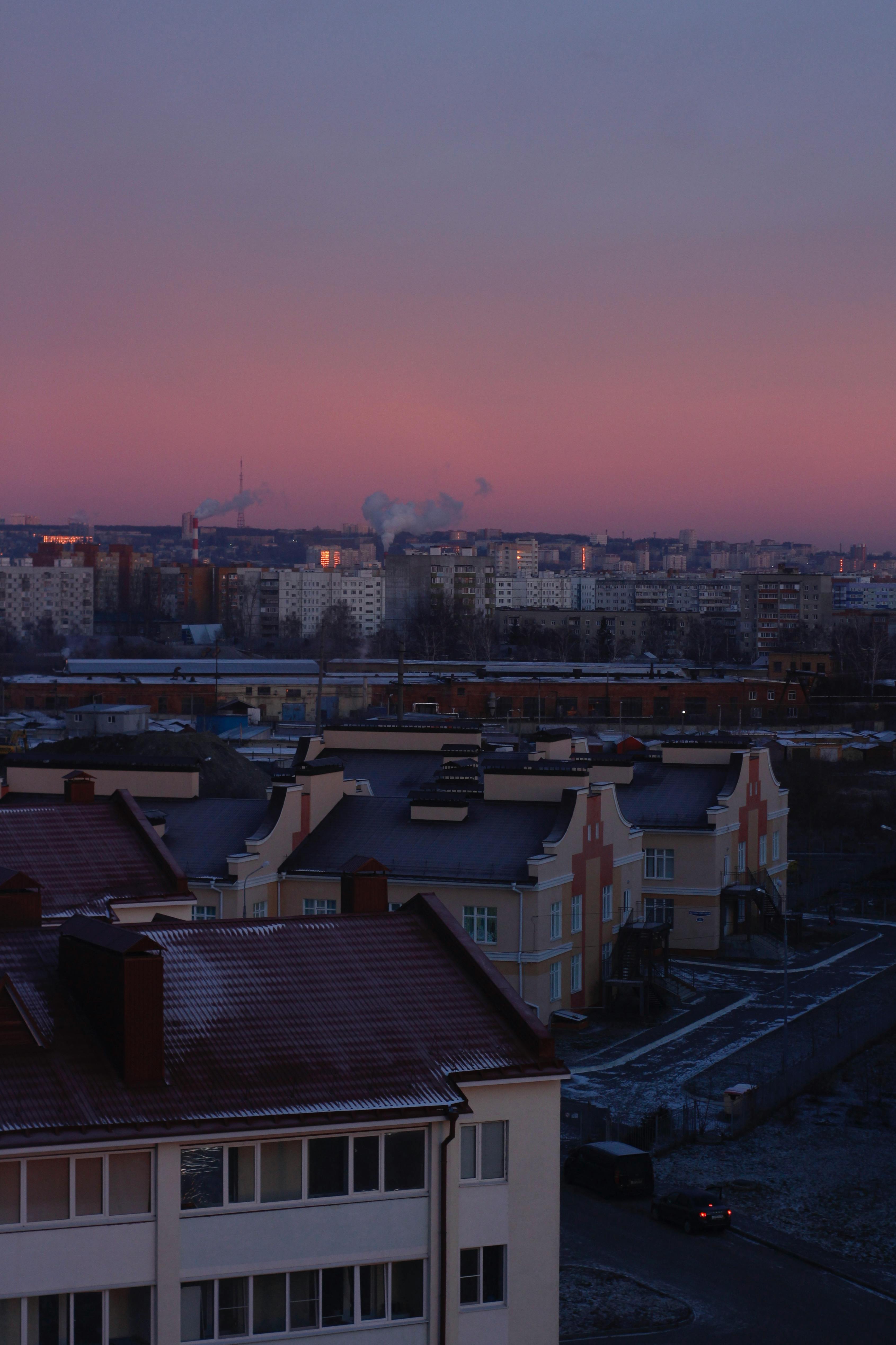Aerial view of a city's rooftops and skyline at twilight with a dramatic sky.