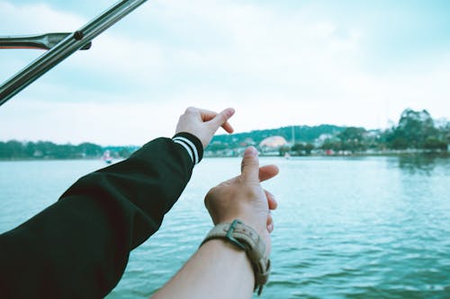 Two Person's Left Hand Making Finger Heart Sign Near Body of Water