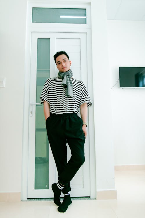 Man in Black and White Striped Shirt Leaning on Door