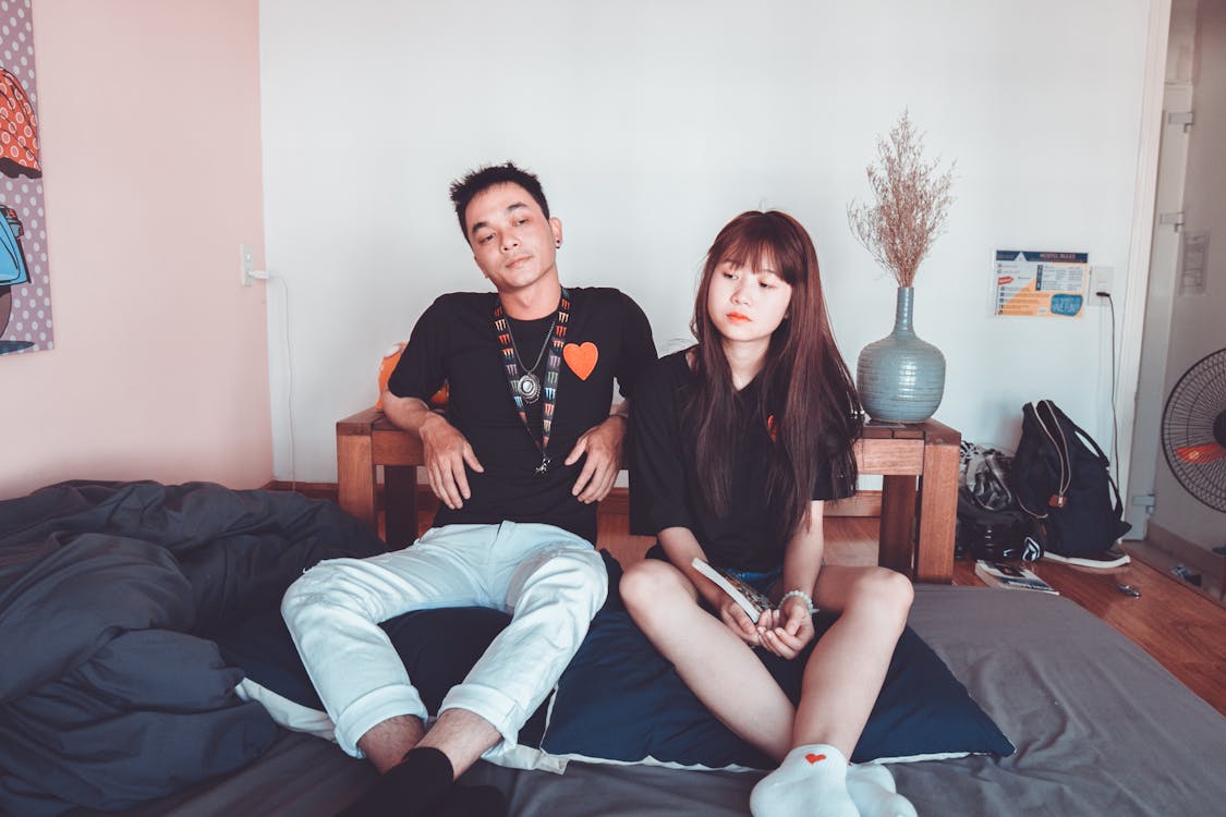 Photo of Woman and Man Sitting Beside Each Other on Mattress