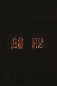 Moody night shot of '2022' string lights on a window, perfect for festive or New Year themes.