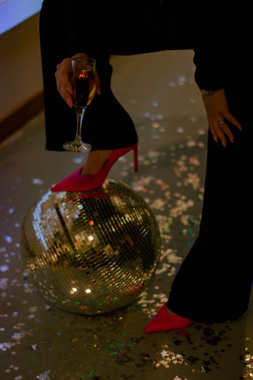 Free A glamorous party setup featuring high heels, a disco ball, and shimmer confetti. Stock Photo