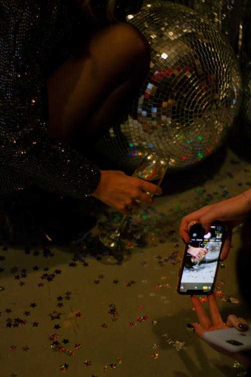 A Person Taking Photo of a Hand Holding a Champagne Glass 