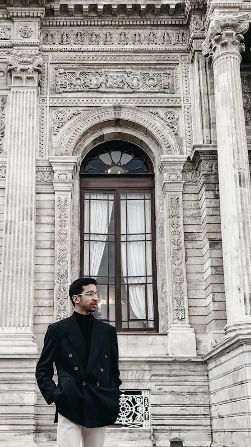 A Man in Black Suit Standing Near the Concrete Building