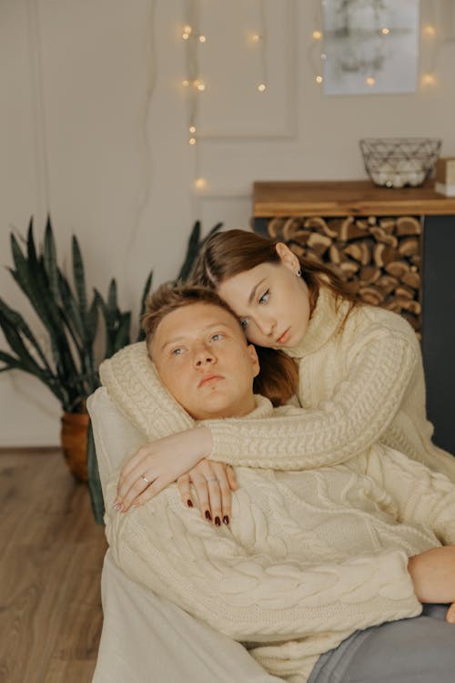 Couple in White Sweaters Embracing on Armchair