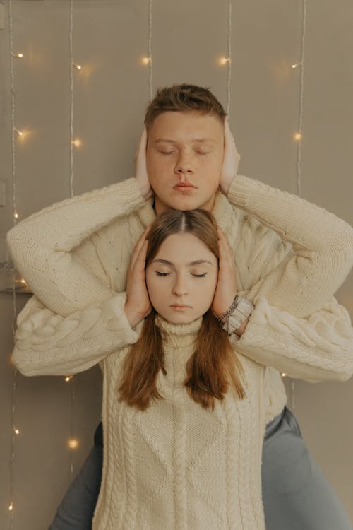 Couple Wearing Warm Sweaters Covering Each Other Ears