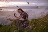 日落时分，一位宁静的女子优雅地坐在草丛中，拥抱宁静