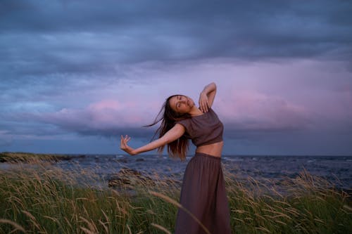 Woman in Brown Dress Dancing on Wheat Field