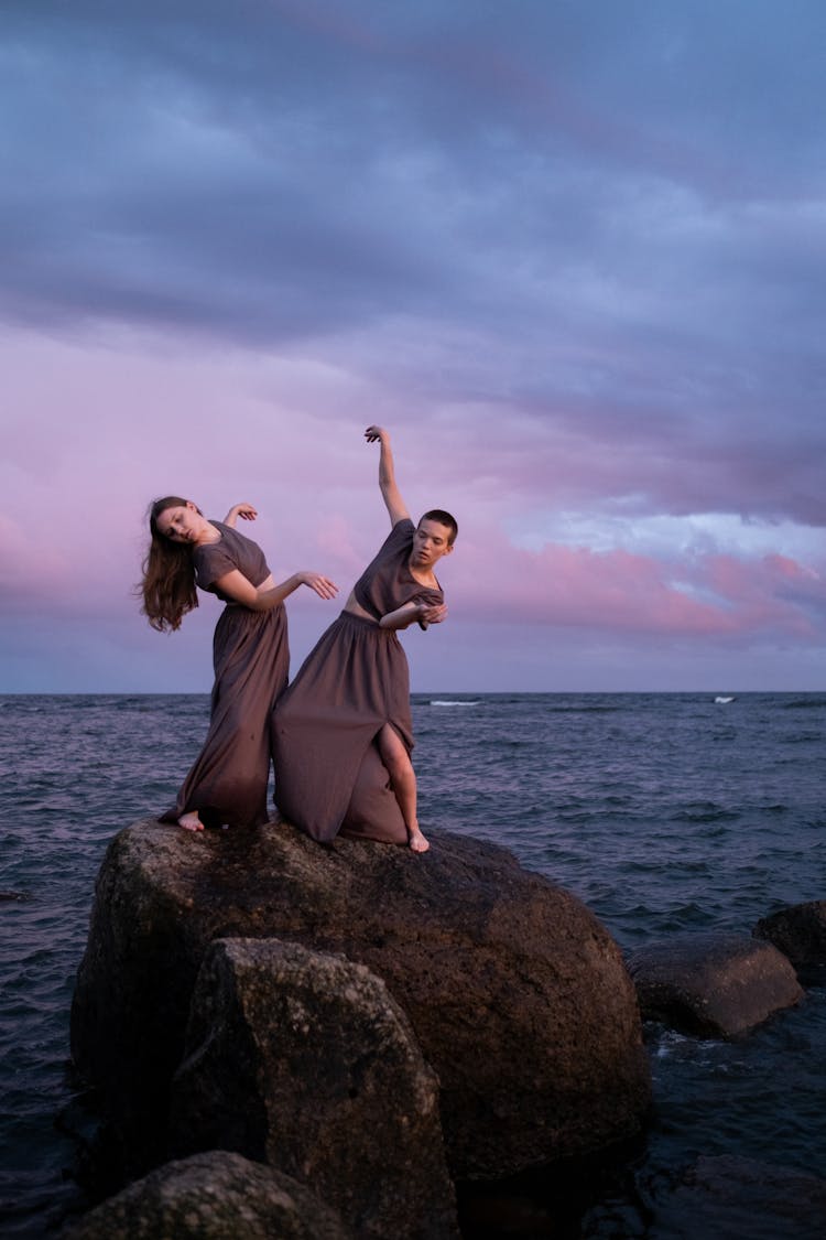 Women Dancing On The Rock Near The Body Of Water