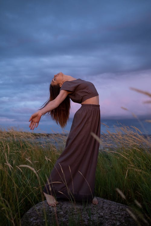 A Woman in a Brown Dress Dancing on a Rock