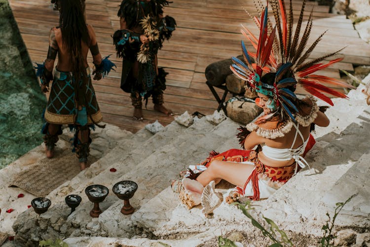 A Woman In A Mayan Outfit Sitting On A Stairway