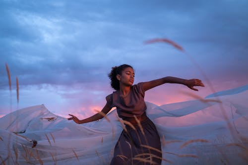 A Woman in a Brown Dress Dancing by a White Cloth