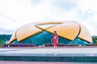 一位身穿红色连衣裙的亚洲妇女站在户外独特的几何建筑结构旁