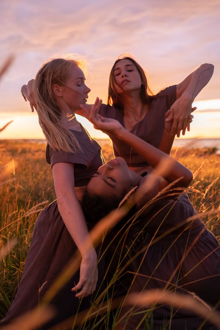 A Group Of Women In Gray Dress Dancing On Grass Field