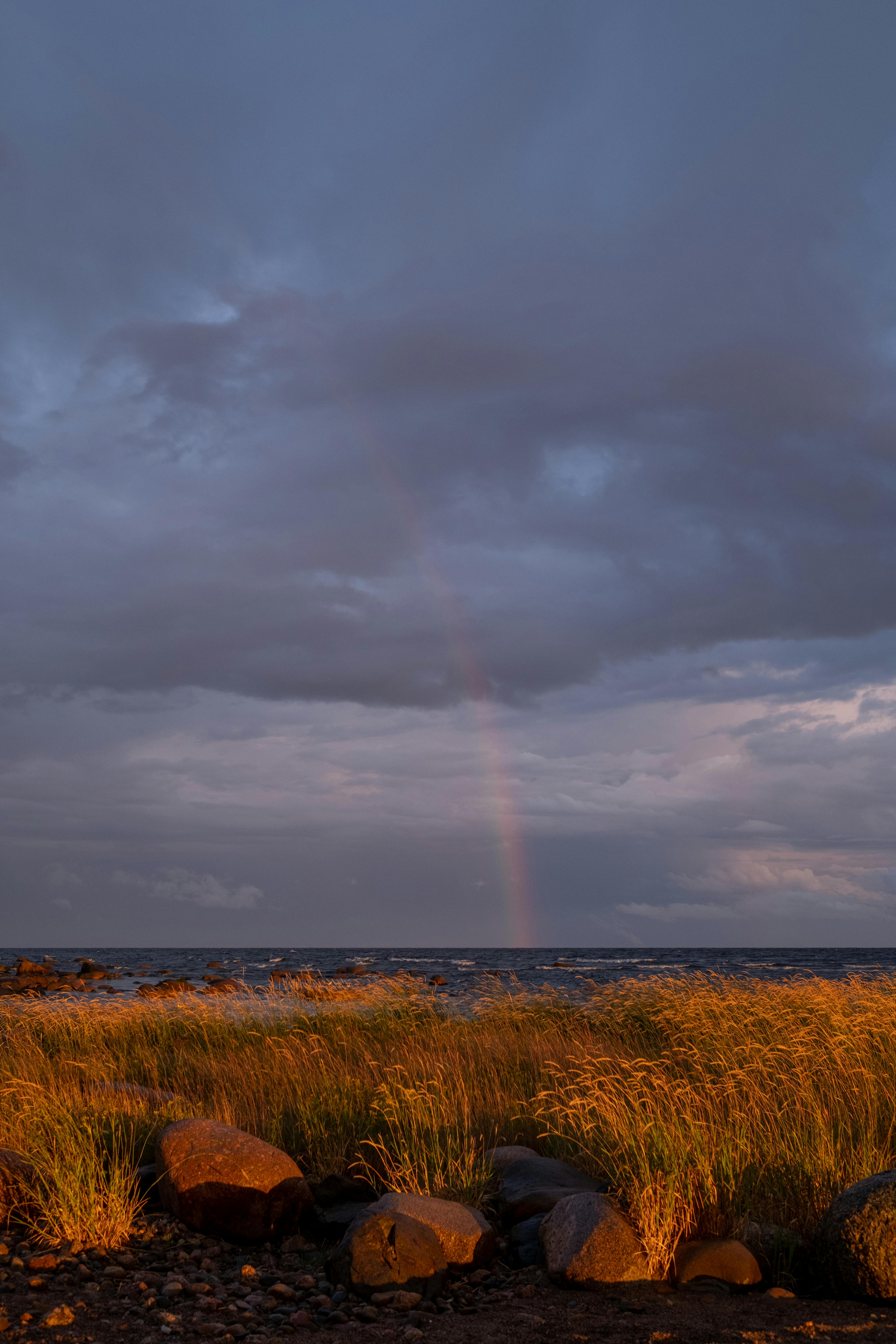 引人注目的沿海景观，有彩虹，宁静的大海上有戏剧性的天空