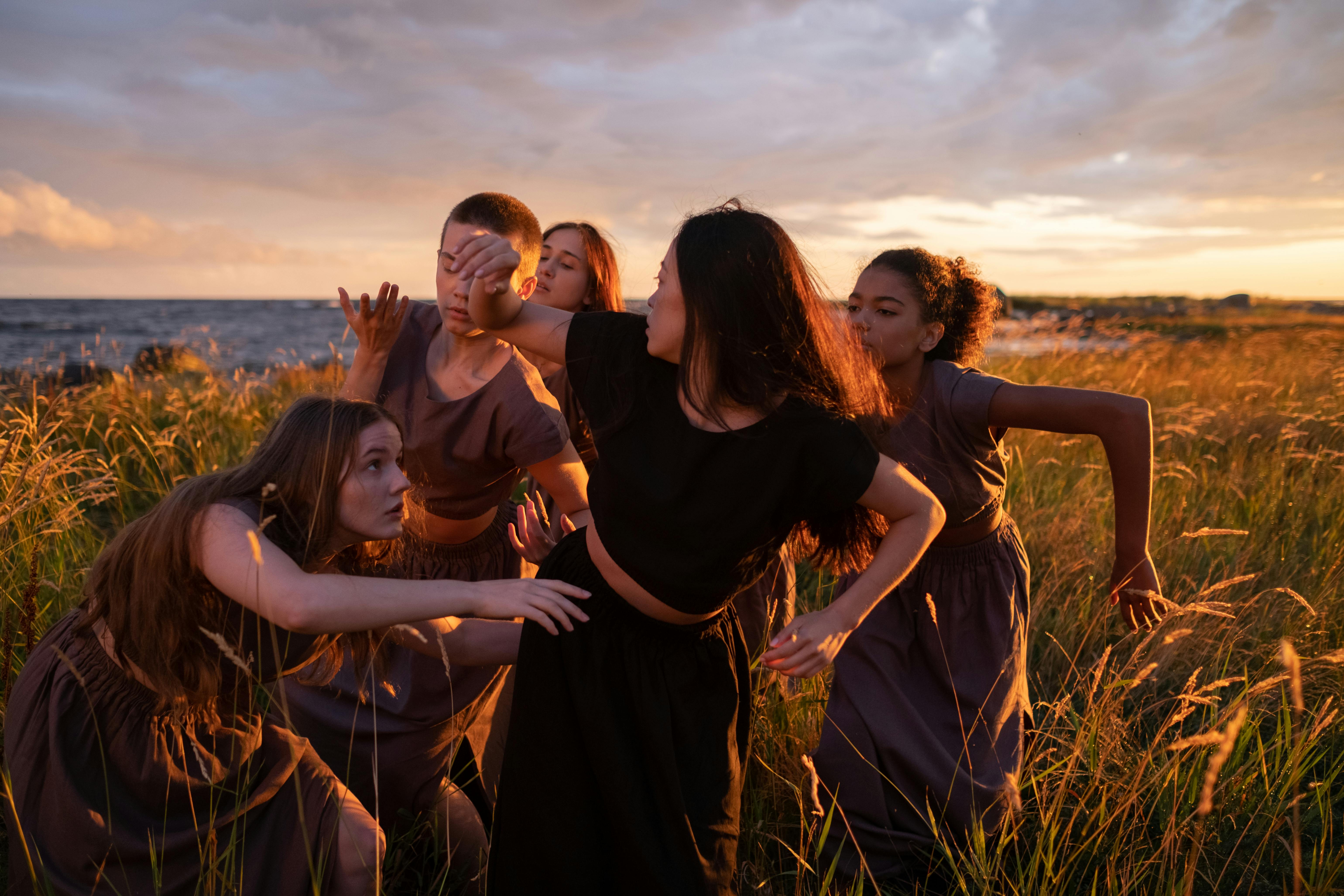 women doing contemporary dance together while standing on a grass field