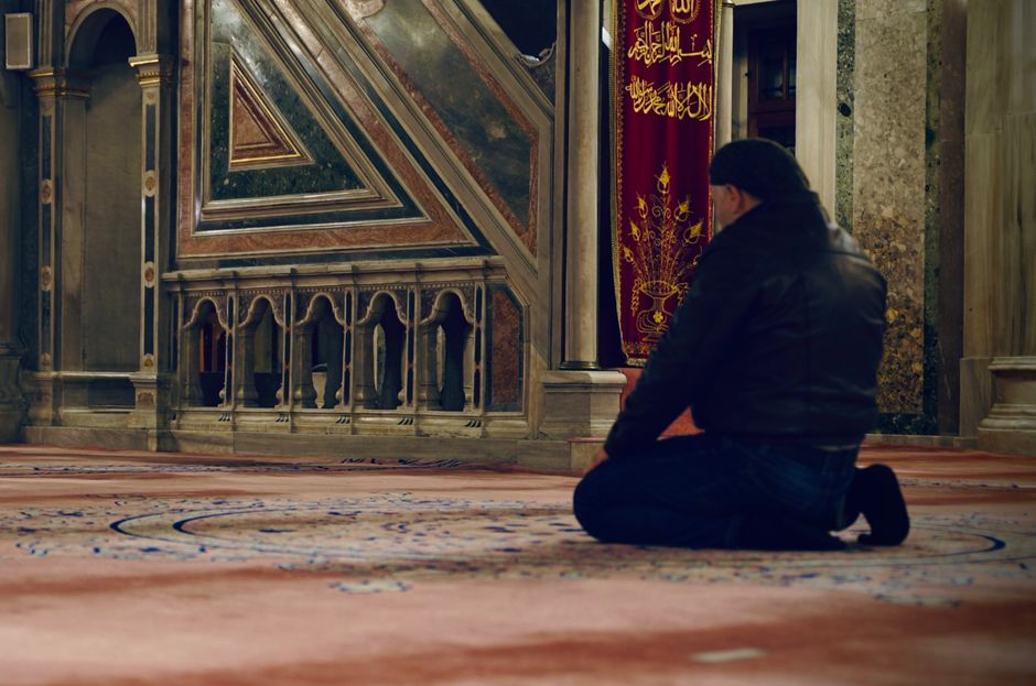 man praying sidewalk city