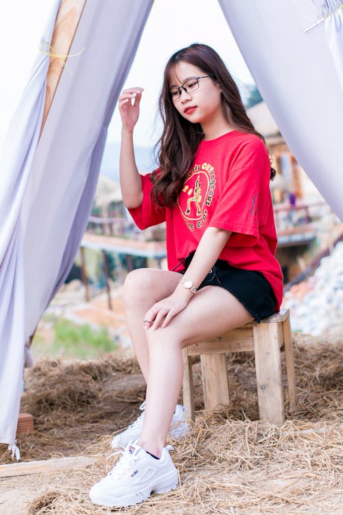 Woman Wearing Red Crew-neck Elbow-sleeved Shirt Sitting on Brown Wooden Stool