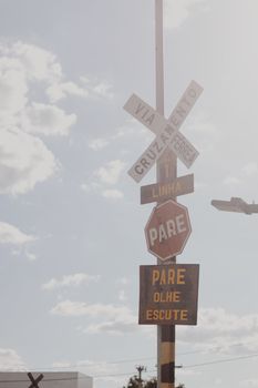 Railroad crossing and stop signs under a clear sky, highlighting safety measures.