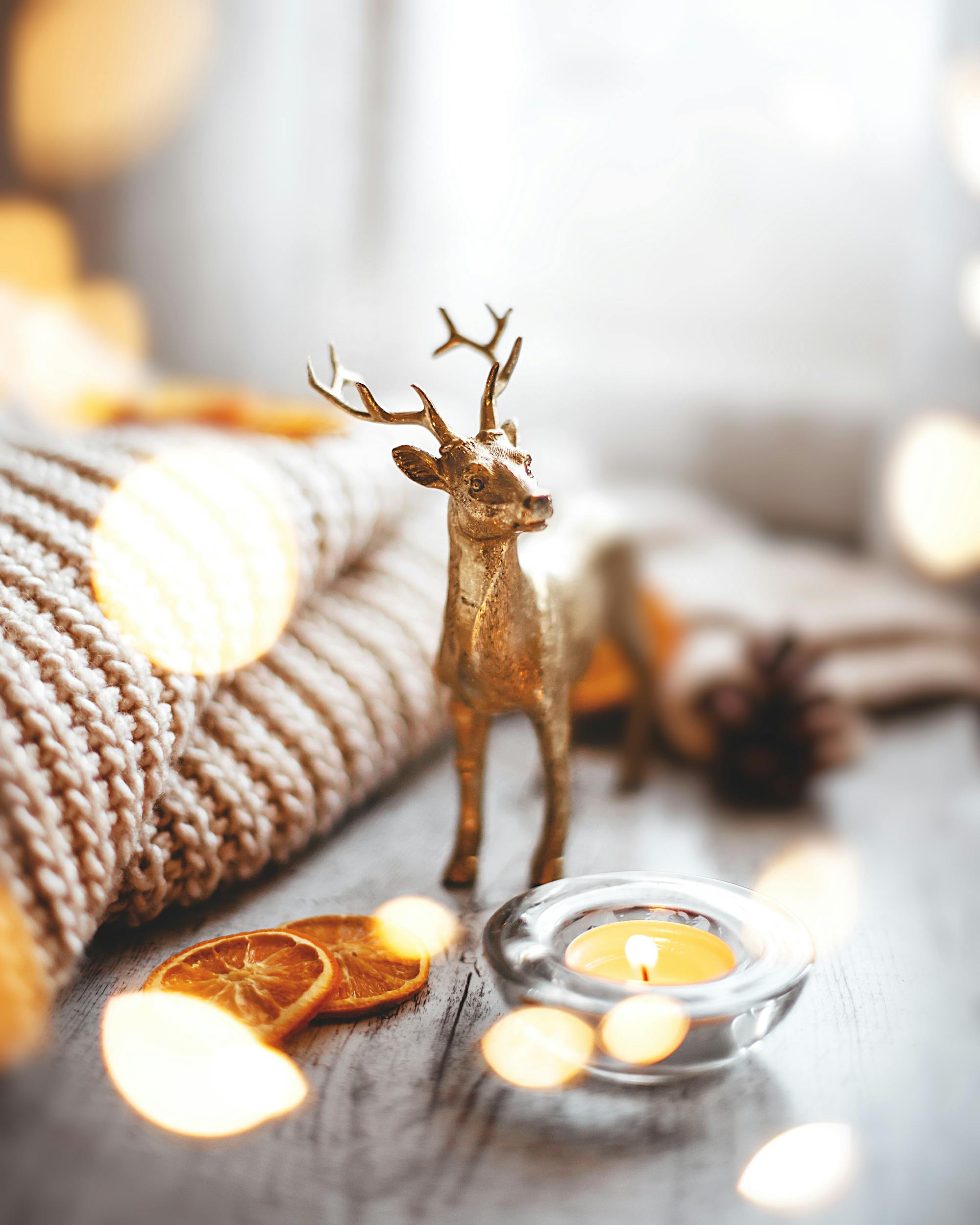 Golden deer figurine with candle and dried orange slices on a cozy winter setup.