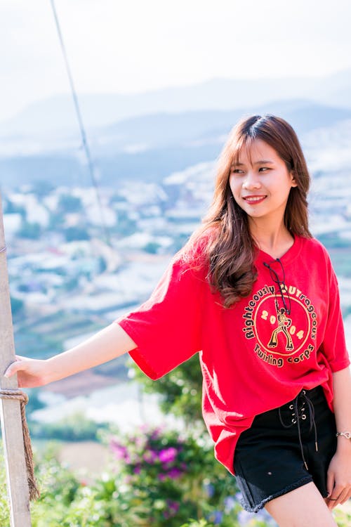 Woman Wearing Red Shirt Standing Beside a Post