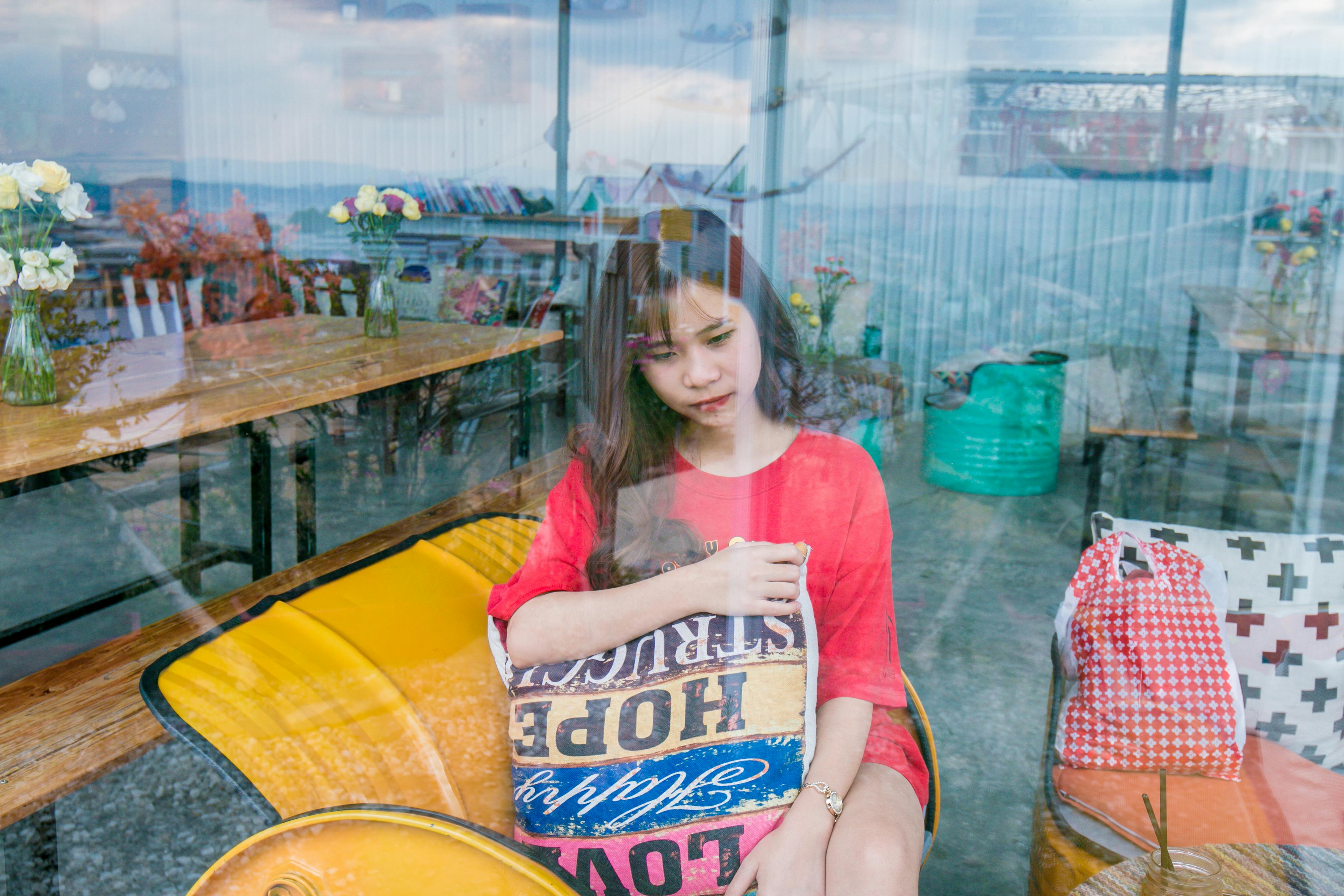 woman wearing red crew neck t shirt sitting on yellow sofa chair