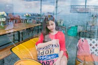 一位年轻女子坐在咖啡馆里，窗上的倒影营造出一种深思的氛围