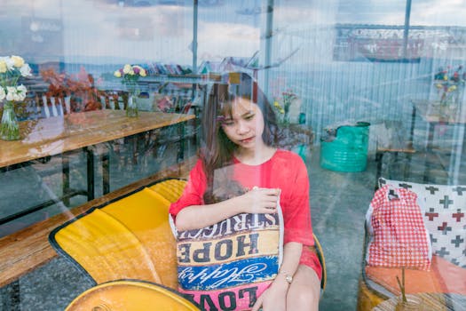 一位年轻女子坐在咖啡馆里，窗上的倒影营造出一种深思的氛围