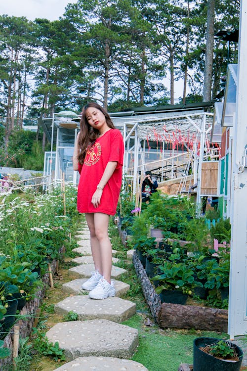 Vrouw, Gekleed In Rood Shirt Met Ronde Hals Tussen Planten In De Buurt Van Bomen