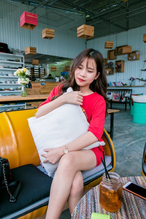 Smiling Woman Wearing Red Lipstick and Red Shirt Holding White Throw Pillow