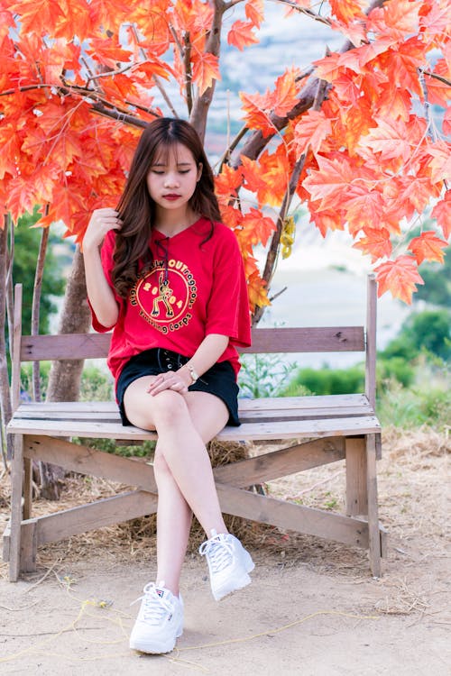 빨간 Leafed 나무 근처에 앉아 빨간 V  넥 셔츠를 입고 여자