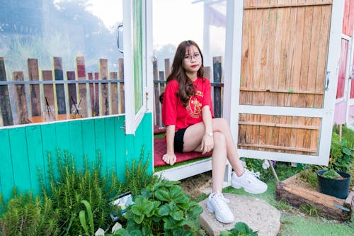 grátis Mulher De Camisa Vermelha E Shortinho Preto Sentada No Chão De Madeira Foto profissional