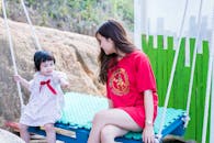 阳光明媚的公园里，母亲和孩子荡着秋千，这是一个快乐而温柔的时刻