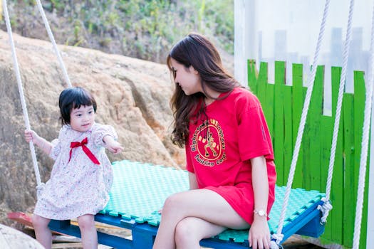 阳光明媚的公园里，母亲和孩子荡着秋千，这是一个快乐而温柔的时刻