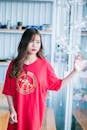 Woman Wearing Red Shirt Standing Near Glass Hanging Decor
