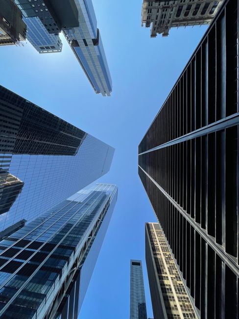 A low-angle view of New York City's iconic skyscrapers reaching towards a clear blue sky.
