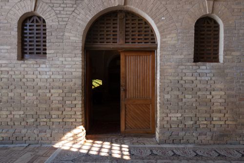 Free An inviting open wooden doorway within a historic brick arched wall, capturing shadows and ambiance. Stock Photo