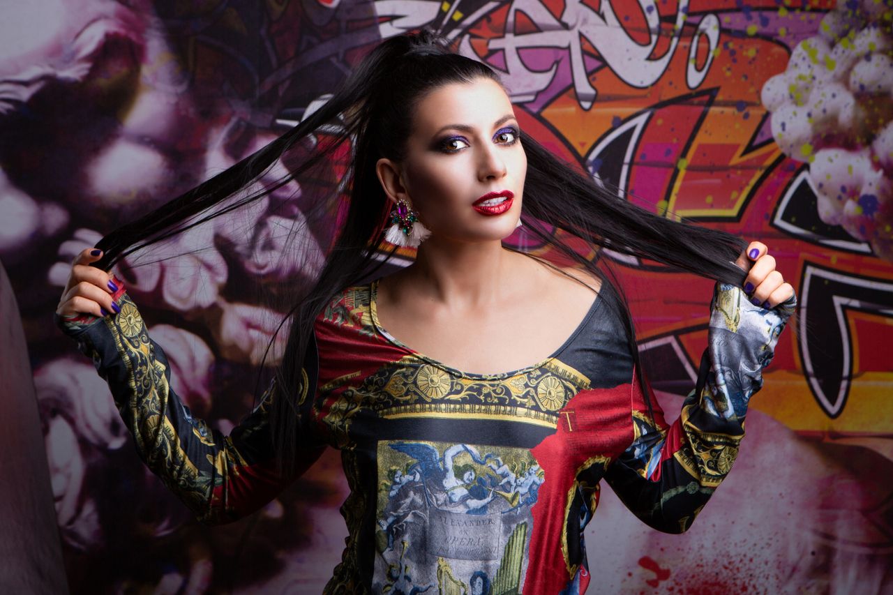 stylish woman in a colorful printed dress poses against a graffiti bac