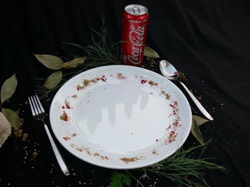 Free A Plate with Spoon and Fork Beside a Coke in Can  Stock Photo