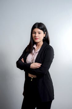 Elegant young businesswoman posing confidently with arms crossed in a professional studio setting.