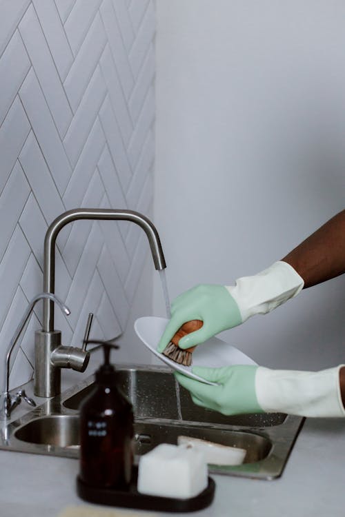 Hands in Latex Gloves while Washing Dishes