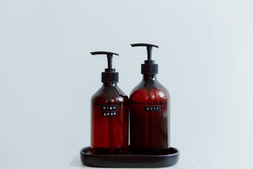 Free Two elegant brown soap dispensers with text labels on a white background, perfect for lifestyle and product photography. Stock Photo