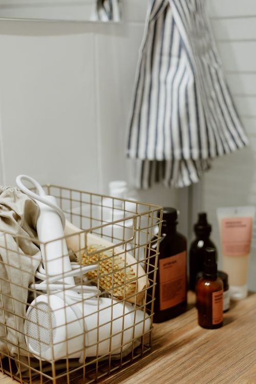 Free Close-up of a bathroom counter with a basket holding a hairdryer and beauty essentials. Stock Photo