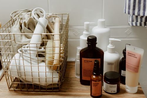 Free Neatly arranged bathroom toiletries and storage items on a wooden surface, featuring cosmetics and a hair dryer. Stock Photo