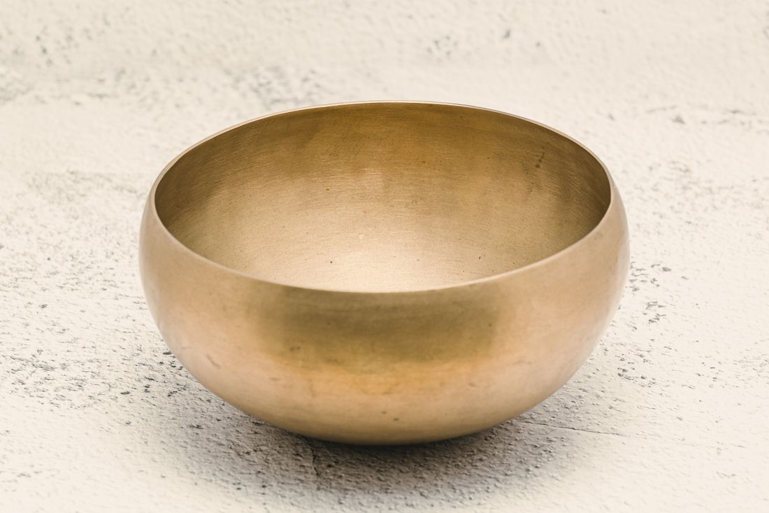 Brass singing bowl on a white surface