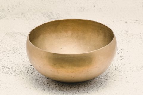 Brass singing bowl on a white surface