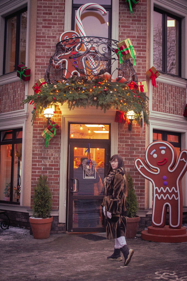 A Woman In Brown Winter Clothing Standing Outside A Commercial Establishment